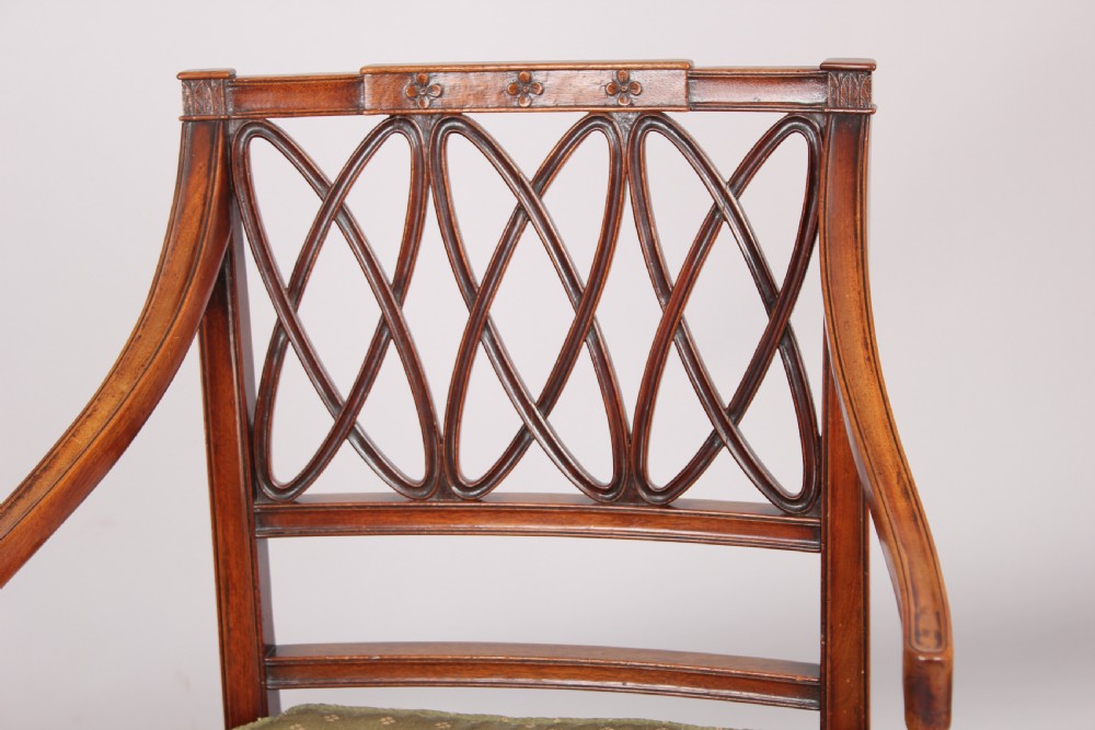 A pair of antique George III mahogany elbow chairs featuring openwork lattice backs, swept armrests, turned front legs, and green seat cushions. View IV