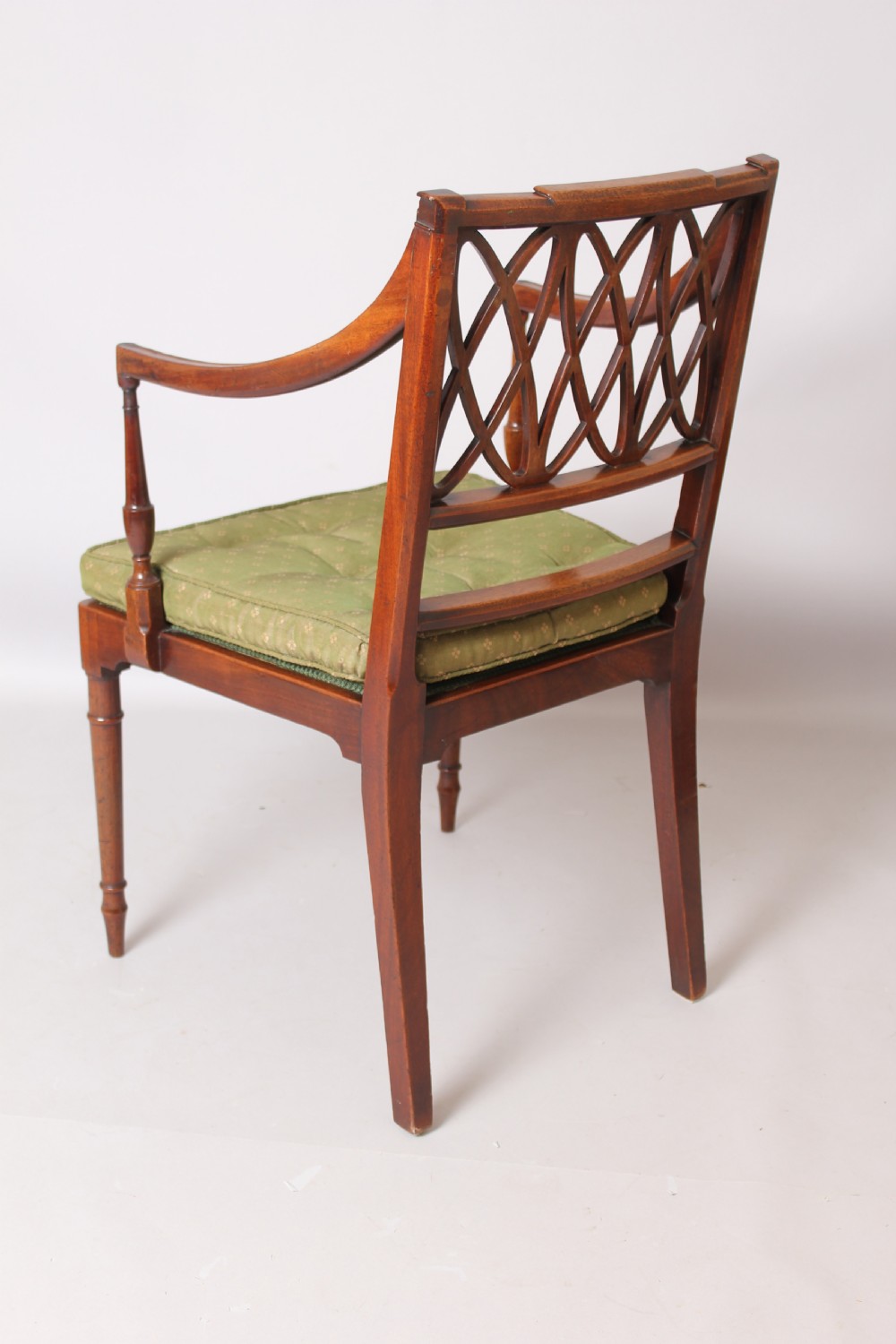 A pair of antique George III mahogany elbow chairs featuring openwork lattice backs, swept armrests, turned front legs, and green seat cushions. View VI