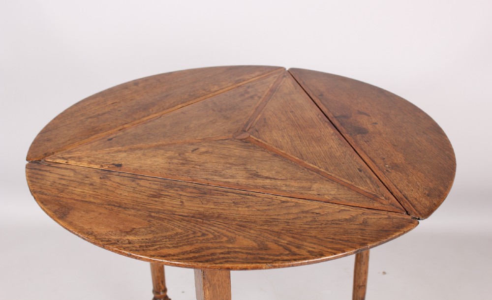 An early 18th-century oak cricket table featuring a triangular top with drop leaves, turned legs, and a triangular stretcher base. View III