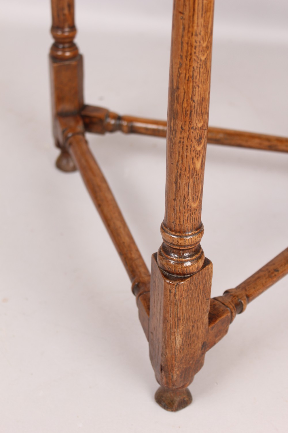 An early 18th-century oak cricket table featuring a triangular top with drop leaves, turned legs, and a triangular stretcher base. View IV