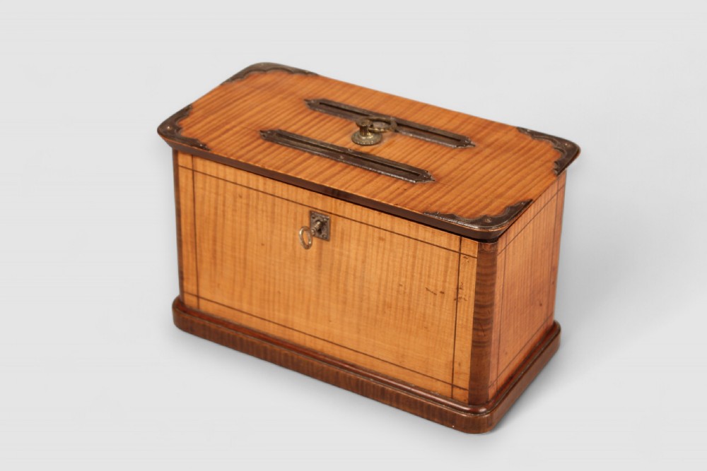 A nineteenth-century rectangular wooden ballot box featuring satinwood veneer with dark wood borders, brass corner mounts, twin top slots with a central ring handle, and a front keyhole. View II
