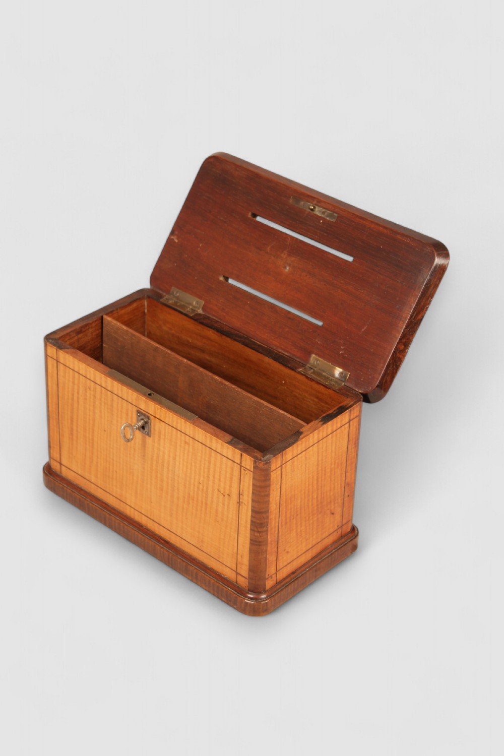 A nineteenth-century rectangular wooden ballot box featuring satinwood veneer with dark wood borders, brass corner mounts, twin top slots with a central ring handle, and a front keyhole. View III