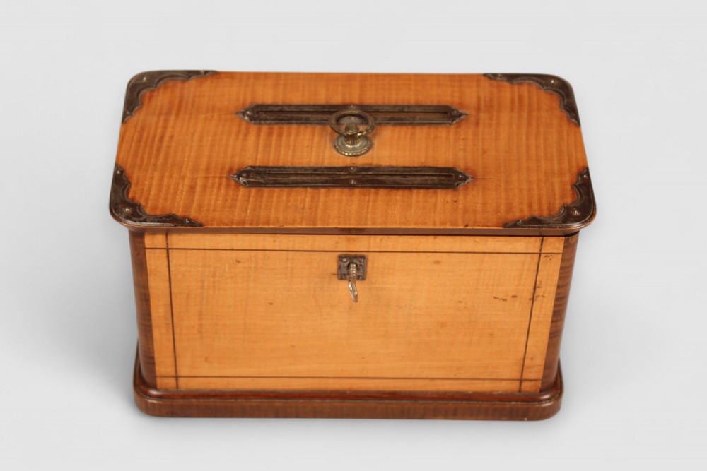A nineteenth-century rectangular wooden ballot box featuring satinwood veneer with dark wood borders, brass corner mounts, twin top slots with a central ring handle, and a front keyhole. View IV