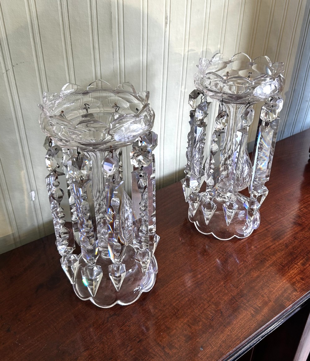 A pair of clear Victorian cut-glass lustres featuring faceted baluster stems, scalloped top rims, and hanging crystal prism drops. View IV