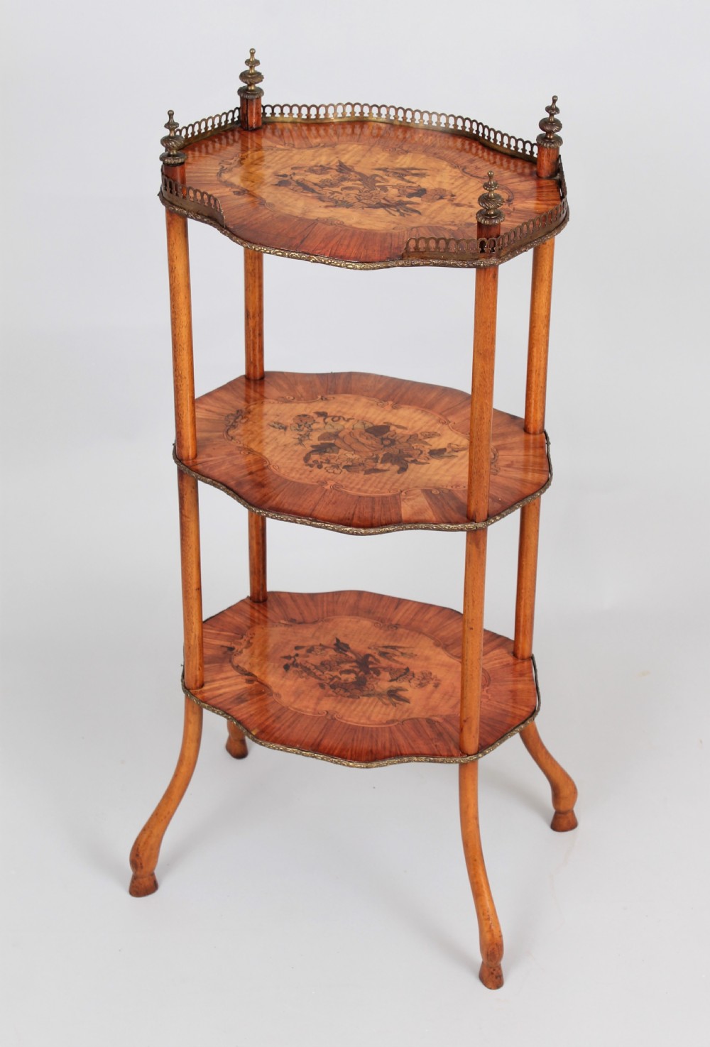 A three-tiered mid 19th century French-style wooden etagere featuring floral marquetry inlays, turned upright supports, brass finials, and a pierced brass gallery on the top shelf. View II