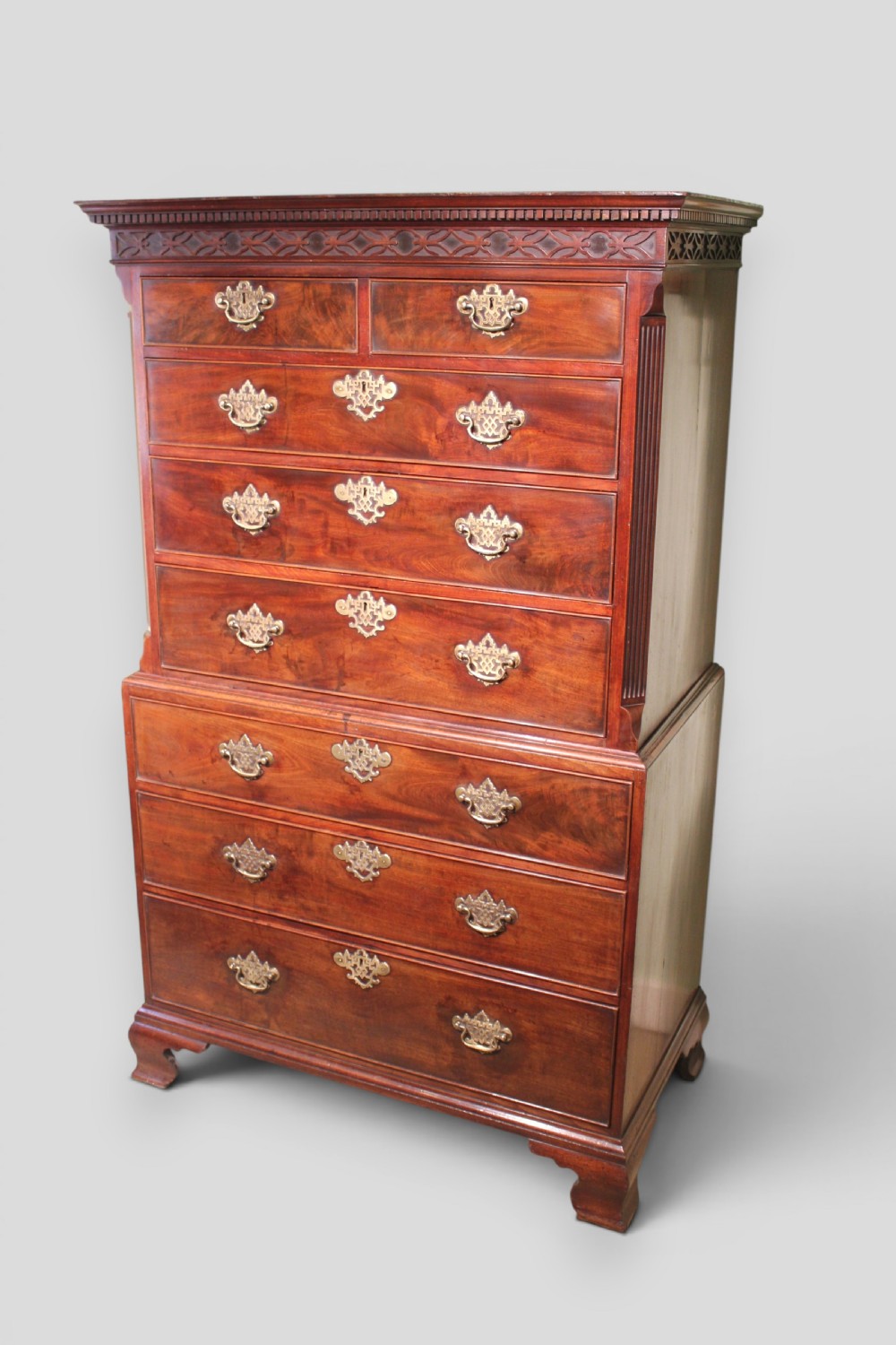 An eighteenth-century mahogany tallboy chest-on-chest featuring a carved frieze, brass swan-neck handles, and bracket feet.