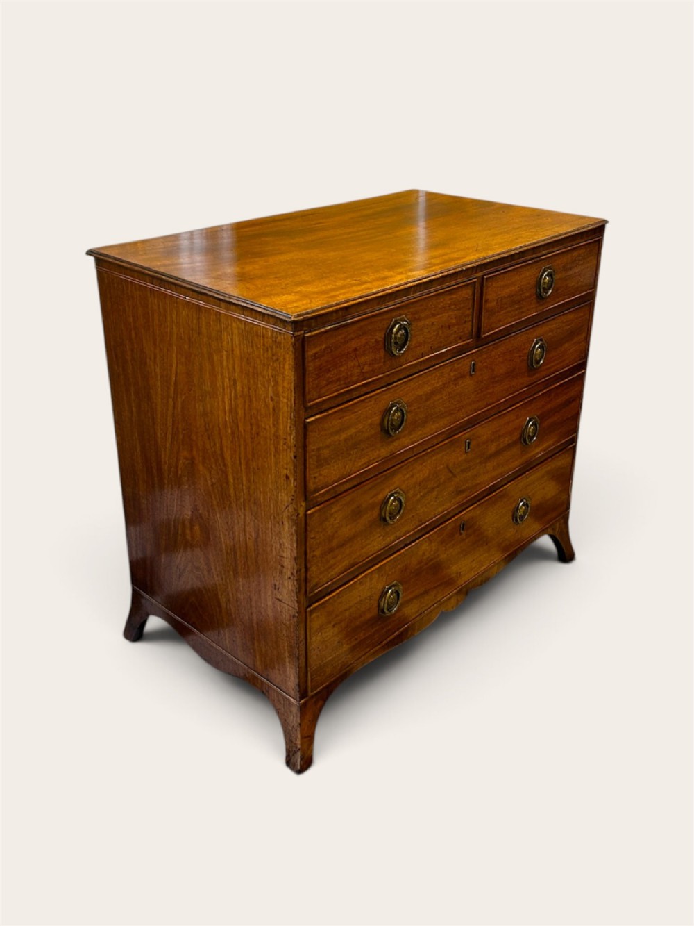 An antique Georgian mahogany chest of drawers featuring two short drawers above three long drawers with brass ring handles and bracket feet. View II