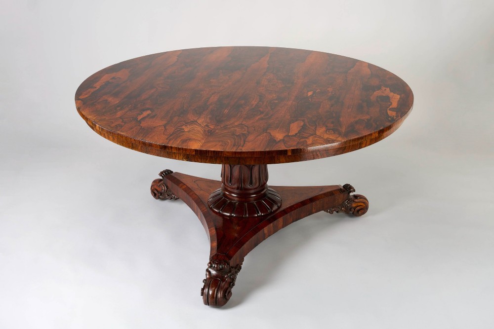 A large George IV circular tilt-top dining or centre table in highly figured book-matched rosewood veneer on a carved triform base. View III