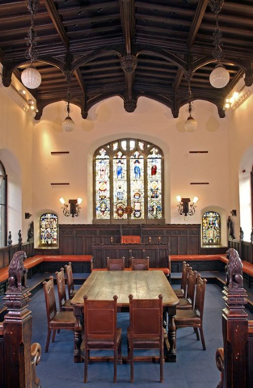 Set of six Gothic Revival oak dining chairs featuring pointed arch upholstered backs, carved cresting, turned finials, and white fabric upholstery. View X