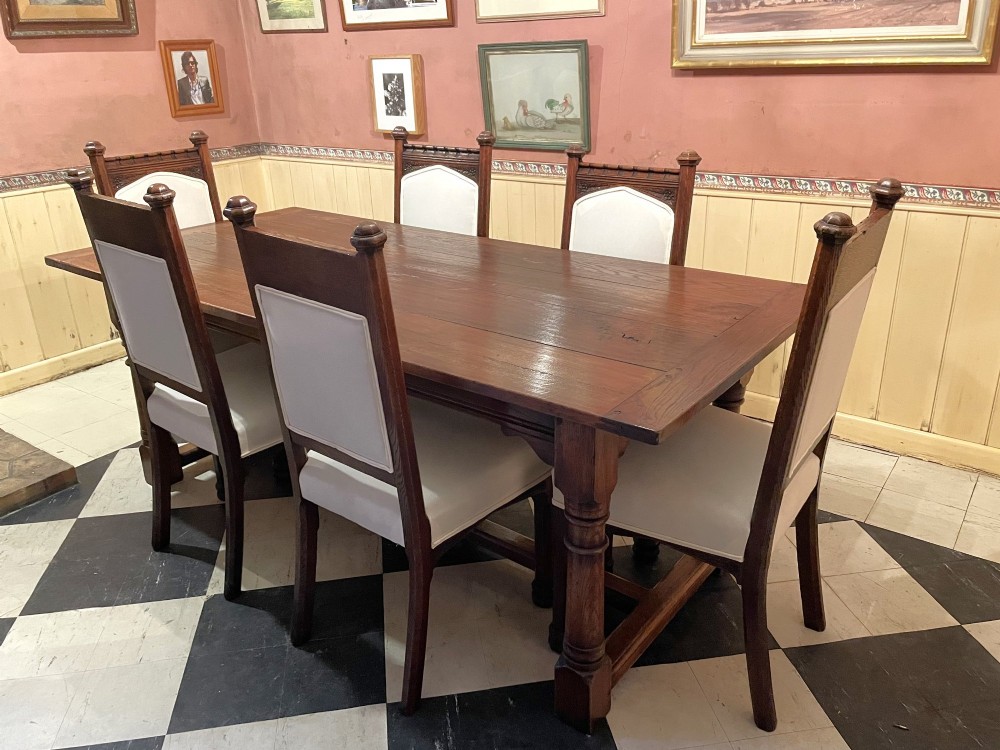 Set of six Gothic Revival oak dining chairs featuring pointed arch upholstered backs, carved cresting, turned finials, and white fabric upholstery. View VIII