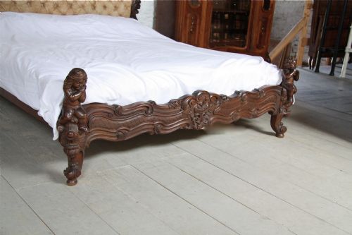 fig 2. Elaborate carved Rococco style dark wood frame upholstered bed with cherubs and matching wall mount bedside cabinets