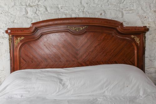fig 1. An antique French mahogany bed frame featuring geometric parquetry panels, fruitwood ribbon marquetry on the footboard, and gilt bronze mounts.