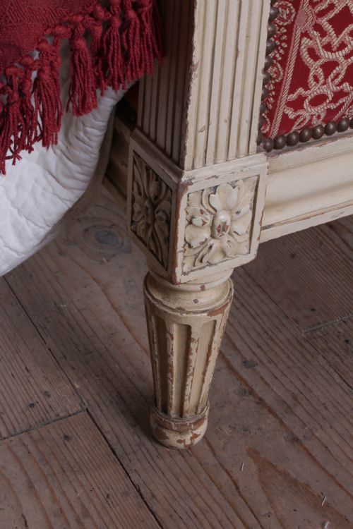fig 2. A French Louis XVI style king size bedstead featuring a cream painted carved timber frame and red patterned damask upholstered headboard and footboard.