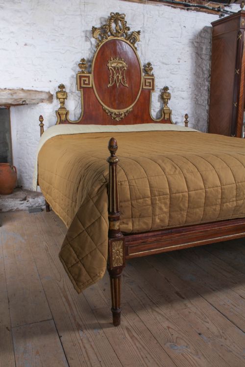 fig 2. An antique mahogany super king bed featuring a high headboard with an oval central medallion, carved giltwood crest, Greek key motifs, and turned posts.