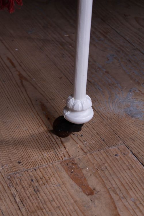 fig 3. A Victorian white painted wrought iron single bed frame featuring ornate scrollwork, floral metal castings, turned brass finials, and castors.