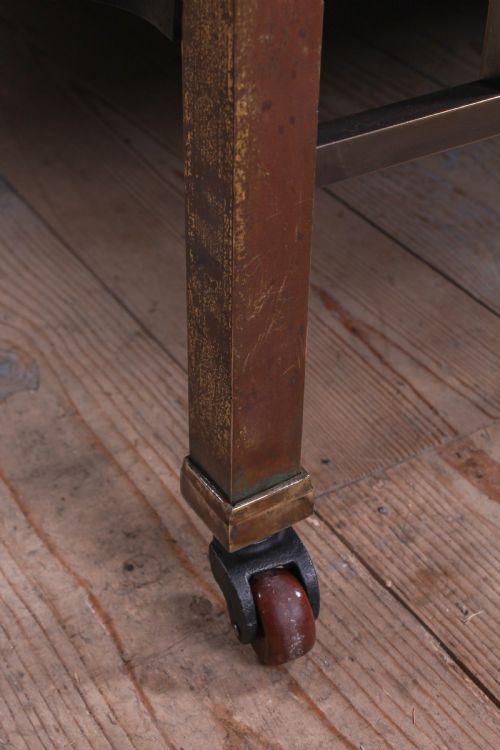 fig 2. An antique Victorian king-size bed frame featuring vertical brass spindles, square corner posts, and an aged metallic patina set on castors.