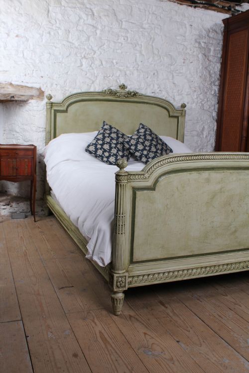 fig 1. A French Louis XVI style king size bedstead in distressed sage green paint with carved fluted posts and decorative molding.