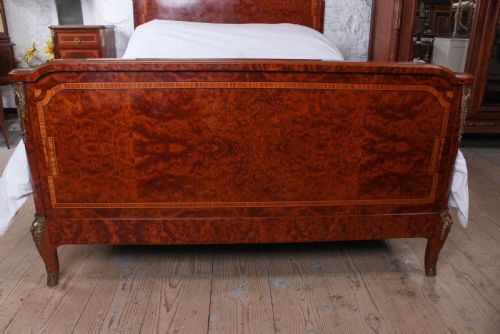 fig 1. A French style kingsize bed frame in warm brown burr mahogany with fruitwood inlay borders and gilt metal corner mounts.