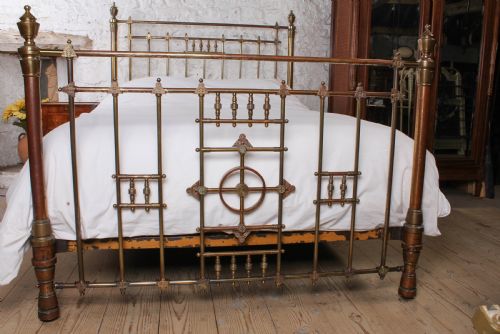 fig 1. A Victorian king-size brass bed frame featuring detailed vertical spindles, geometric central motifs on the footboard, and turned corner posts with finials.