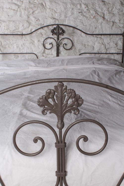 fig 1. A king size Portuguese iron bed frame painted in a neutral taupe colour, featuring decorative scrollwork and a central shell motif on both the headboard and footboard.