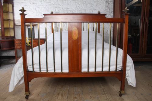 fig 1. An antique mahogany double bed frame featuring polished brass upright spindles, brass urn finials, and an oval marquetry medallion inlaid on the footboard.
