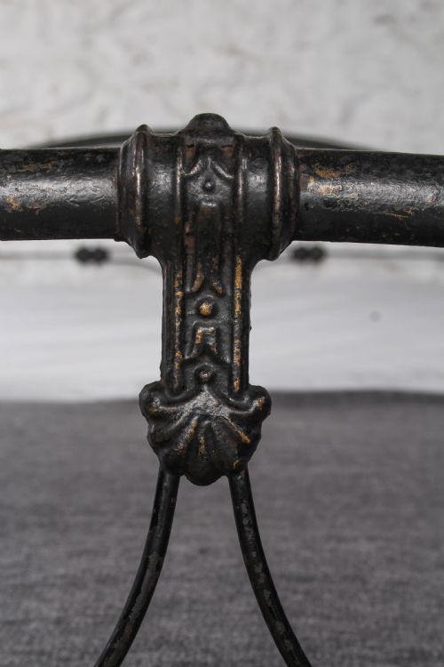fig 3. An antique dark wrought iron double bed frame featuring arched headboard and footboard rails with decorative cast rosettes.