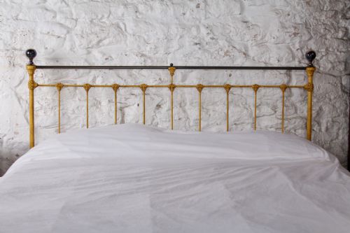 fig 1. A king-size yellow painted iron bedstead featuring a vertical spindle headboard with a brass top rail and no footboard.