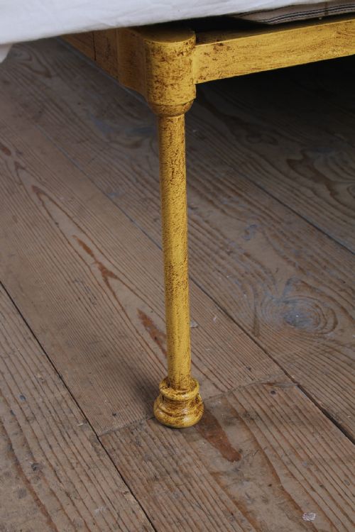 fig 2. A king-size yellow painted iron bedstead featuring a vertical spindle headboard with a brass top rail and no footboard.