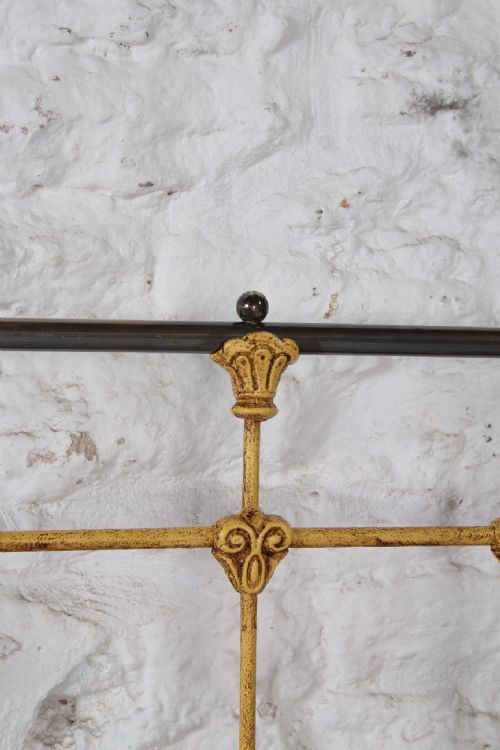 fig 3. A king-size yellow painted iron bedstead featuring a vertical spindle headboard with a brass top rail and no footboard.