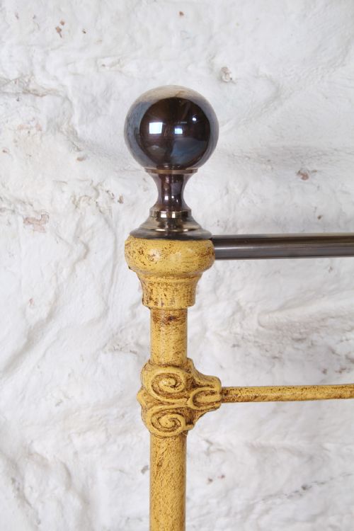 fig 4. A king-size yellow painted iron bedstead featuring a vertical spindle headboard with a brass top rail and no footboard.