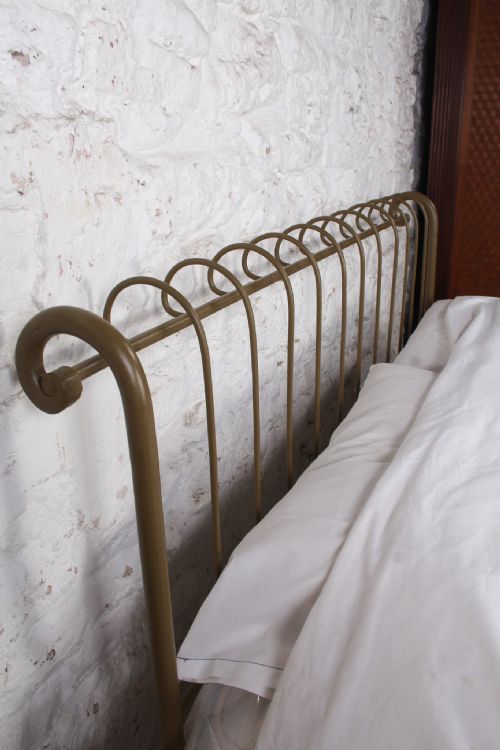 fig 1. A forged iron king-size bedstead featuring an arched looped headboard and an open footless frame.