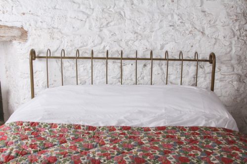 fig 2. A forged iron king-size bedstead featuring an arched looped headboard and an open footless frame.