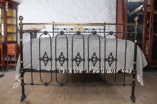 fig 1. A Victorian five-foot king-size bedstead featuring a black japanned cast iron frame with vertical arched spindles, central diamond motifs, and brass top rails with brass finials.