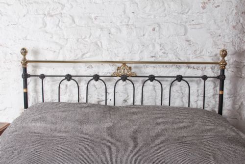 fig 2. A Victorian five-foot king-size bedstead featuring a black japanned cast iron frame with vertical arched spindles, central diamond motifs, and brass top rails with brass finials.