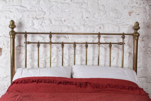fig 2. A Victorian brass king-size bed frame featuring turned upright posts, urn finials, vertical decorative spindles, circular roundels, and original castors.