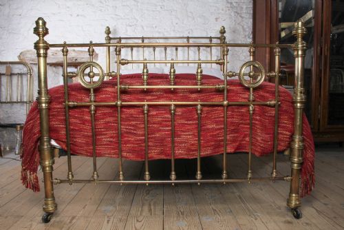 fig 3. A Victorian brass king-size bed frame featuring turned upright posts, urn finials, vertical decorative spindles, circular roundels, and original castors.