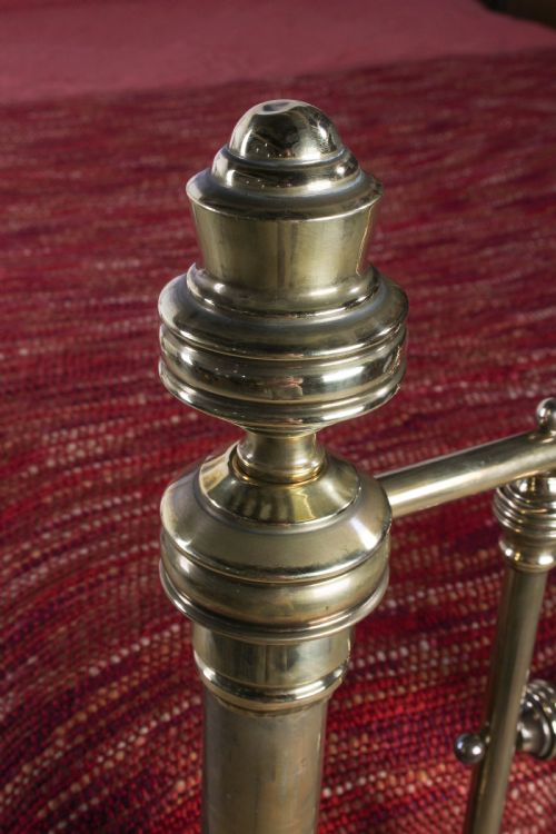 fig 4. A Victorian brass king-size bed frame featuring turned upright posts, urn finials, vertical decorative spindles, circular roundels, and original castors.