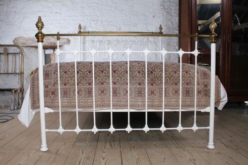 fig 1. A Victorian white painted iron bedstead featuring brass top rails and brass urn finials on the headboard and footboard.