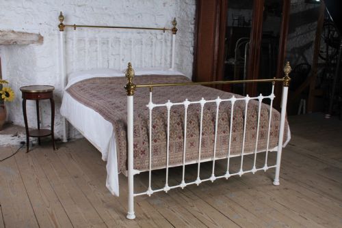 fig 2. A Victorian white painted iron bedstead featuring brass top rails and brass urn finials on the headboard and footboard.