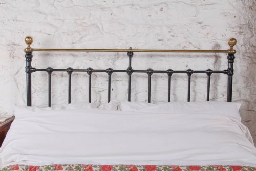 fig 1. A Victorian double bedstead featuring a black painted cast iron frame, brass top rails, and spherical brass finials.