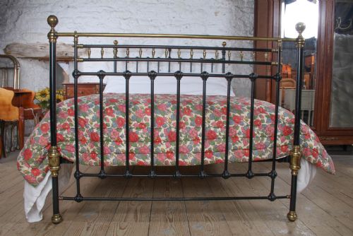 fig 2. A Victorian double bedstead featuring a black painted cast iron frame, brass top rails, and spherical brass finials.