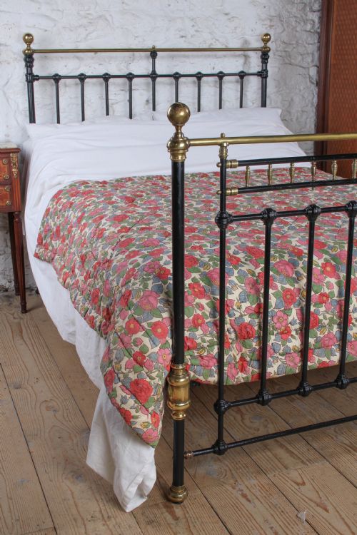 fig 3. A Victorian double bedstead featuring a black painted cast iron frame, brass top rails, and spherical brass finials.