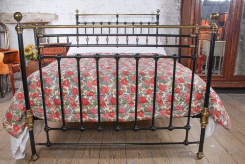 fig 4. A Victorian double bedstead featuring a black painted cast iron frame, brass top rails, and spherical brass finials.