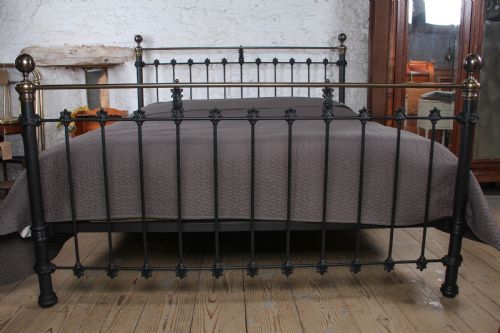 fig 3. A super king size bedstead featuring a black iron frame with vertical spindles, cast rosettes, and brass top rails with brass ball finials.