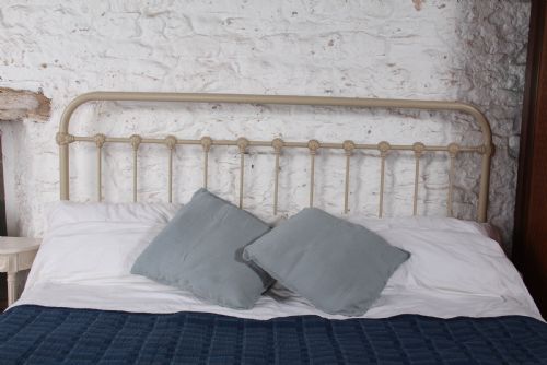 fig 2. A cream-painted French iron super king size bed frame featuring vertical spindles and cast iron ornamental details.