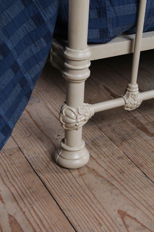 fig 4. A cream-painted French iron super king size bed frame featuring vertical spindles and cast iron ornamental details.