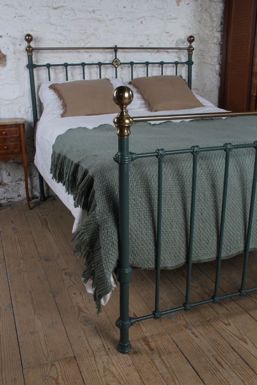 fig 2. A Victorian metal bedstead featuring dark green painted iron uprights, vertical spindles, brass top rails, and brass finials.