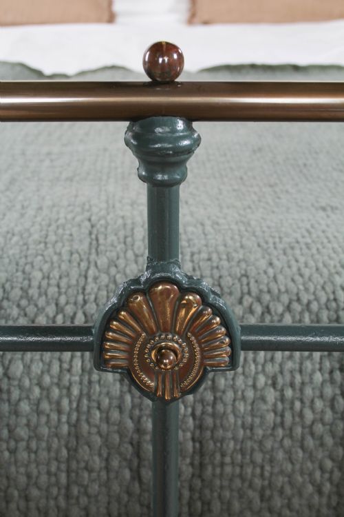 fig 4. A Victorian metal bedstead featuring dark green painted iron uprights, vertical spindles, brass top rails, and brass finials.
