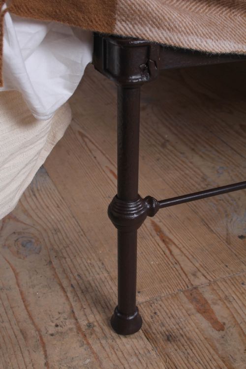 fig 4. An antique dark iron king size bedstead featuring an arched headboard with decorative scrollwork and a low footrail design.