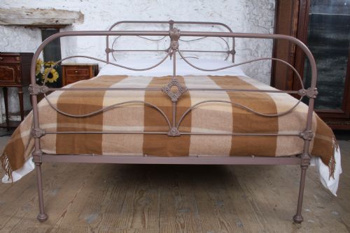 fig 1. An antique Irish double bed frame constructed from painted iron with curved metal scrollwork and decorative cast medallions.